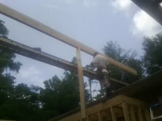 Carpenter setting a ridge beam over a new addition frame — Ice Dam Removal by Roofing Brothers in Sand Springs