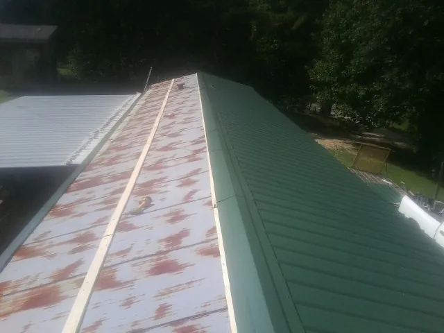 Old rusted panels beside newly installed green metal roofing — Wind Damage Roof Repair by Roofing Brothers in Sand Springs