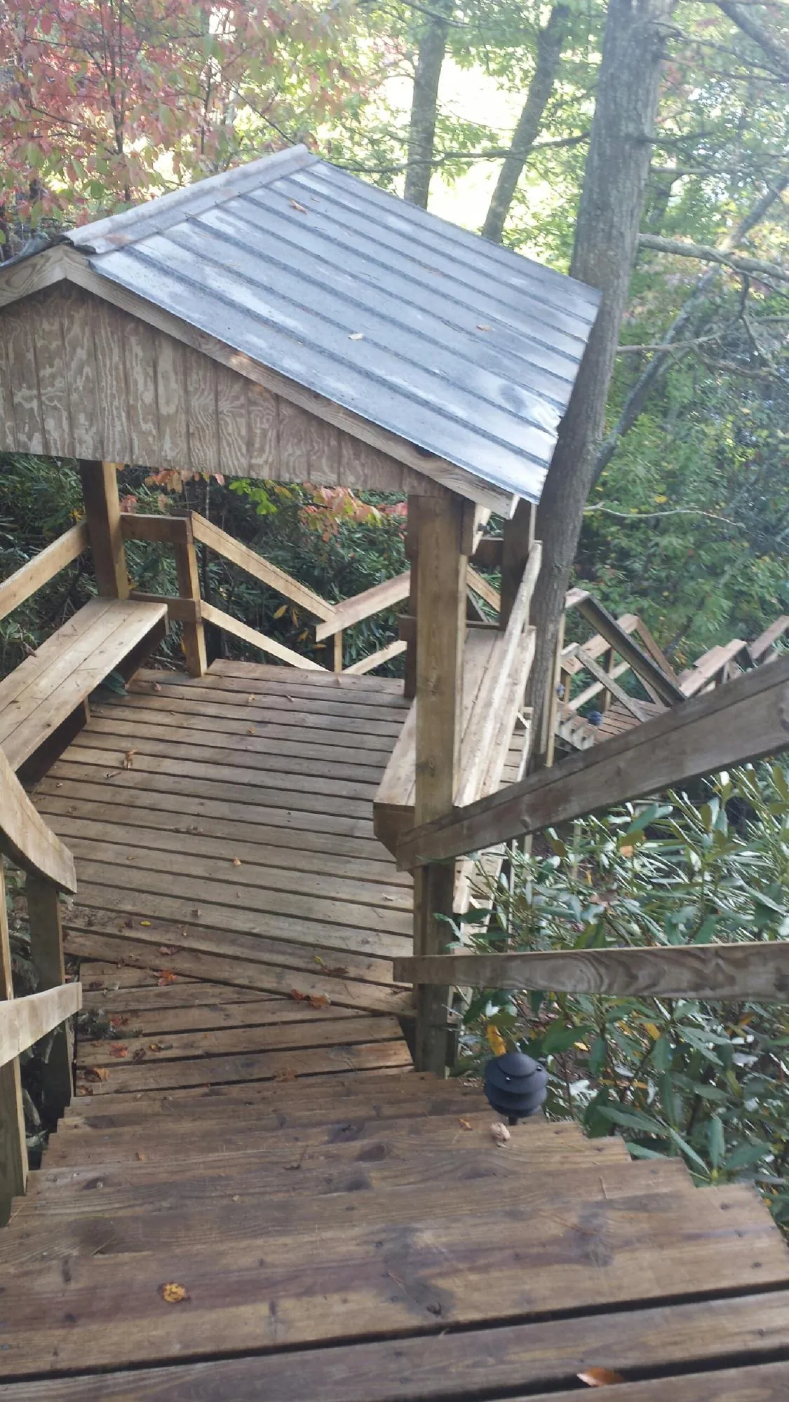 Metal roofed shelter over wooden steps on a wooded walkway — Skylight Repair & Installation work by our crew in Sand Springs